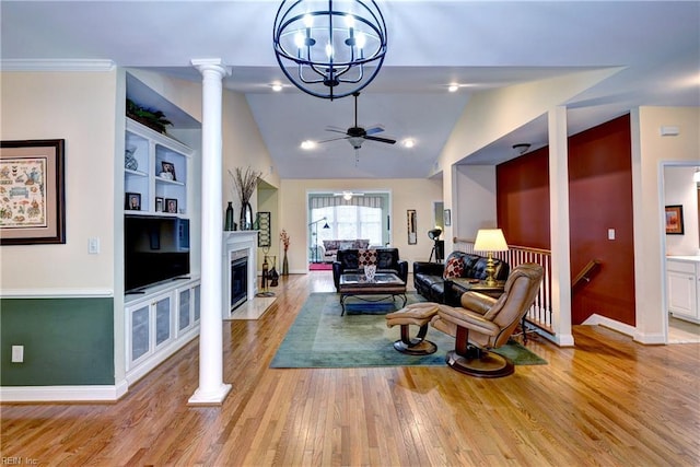 living area with built in shelves, a fireplace with flush hearth, vaulted ceiling, light wood-type flooring, and ornate columns