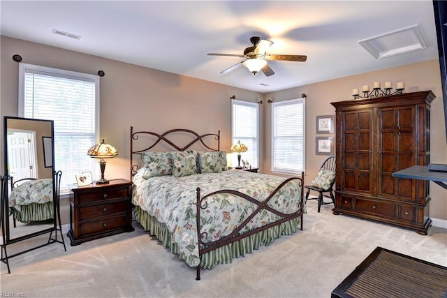 bedroom featuring attic access, light colored carpet, visible vents, and a ceiling fan