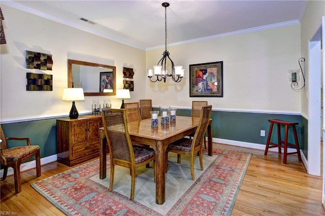 dining room with a notable chandelier, light wood finished floors, visible vents, ornamental molding, and baseboards