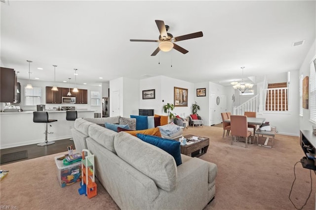 living area featuring recessed lighting, ceiling fan with notable chandelier, visible vents, baseboards, and stairway