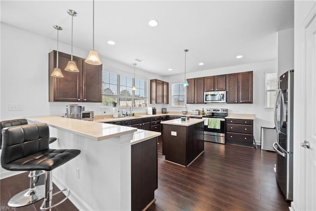 kitchen featuring stainless steel appliances, recessed lighting, light countertops, dark wood-type flooring, and a peninsula