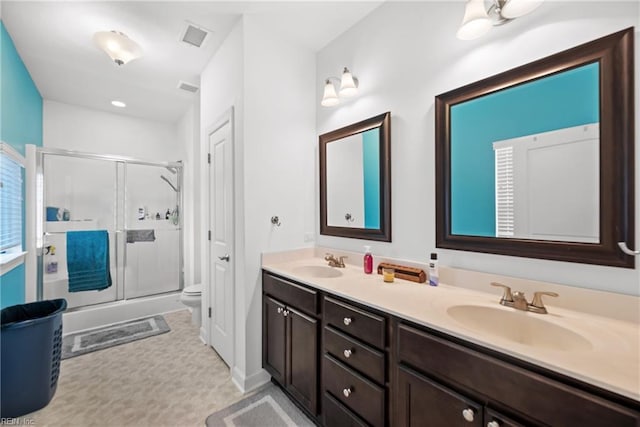 full bathroom featuring visible vents, a sink, a shower stall, and double vanity