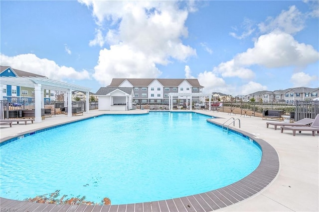 community pool featuring a residential view, a patio area, fence, and a pergola