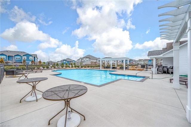 pool with a residential view, a patio area, fence, and a pergola