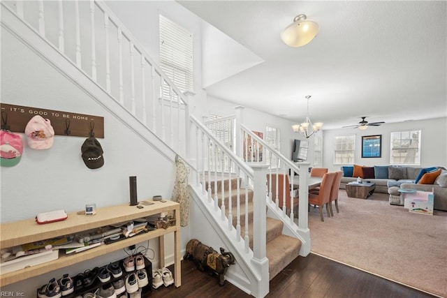 stairway featuring ceiling fan with notable chandelier and wood finished floors