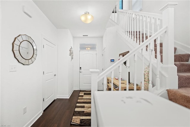 entrance foyer with stairway, dark wood finished floors, and baseboards