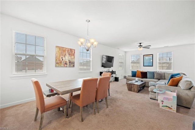 dining area with baseboards, ceiling fan with notable chandelier, and light colored carpet