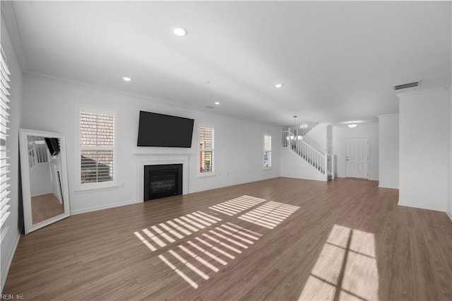 unfurnished living room featuring plenty of natural light, a fireplace, wood finished floors, and visible vents