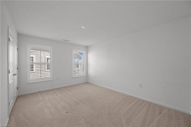 empty room featuring light carpet and baseboards