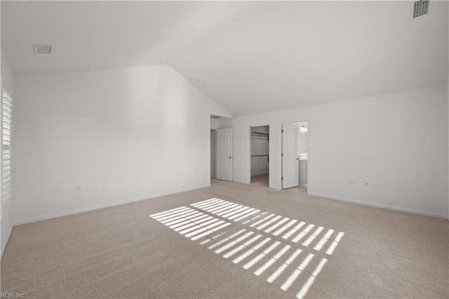 unfurnished bedroom featuring lofted ceiling, visible vents, light carpet, and baseboards