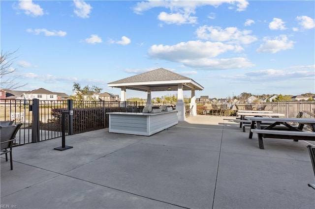 view of patio / terrace with a gazebo, outdoor dining area, fence, and a residential view