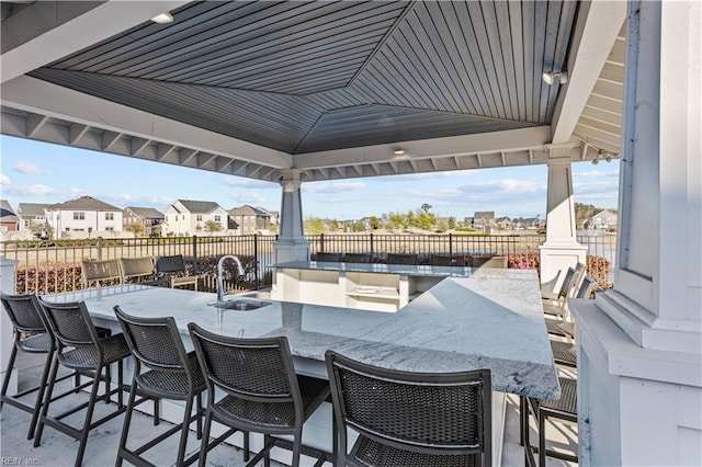 view of patio / terrace with outdoor dry bar, a gazebo, a sink, and a residential view