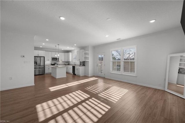 unfurnished living room with a textured ceiling, baseboards, wood finished floors, and recessed lighting