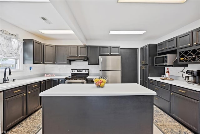 kitchen featuring visible vents, stainless steel appliances, light countertops, under cabinet range hood, and a sink