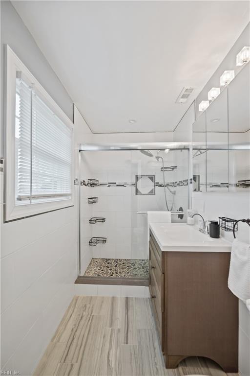 full bathroom with a stall shower, visible vents, and vanity