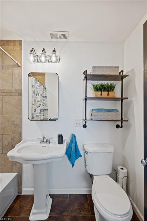 bathroom featuring toilet, baseboards, visible vents, and shower / washtub combination