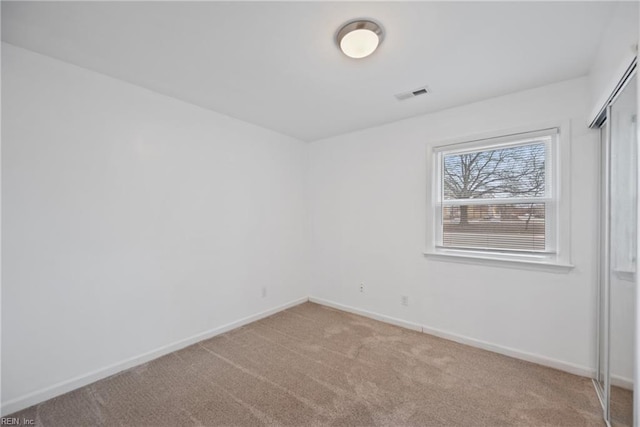 carpeted empty room with visible vents and baseboards