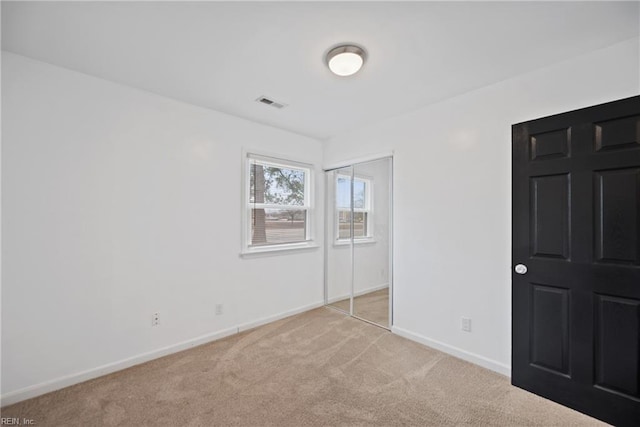 unfurnished bedroom featuring carpet, a closet, visible vents, and baseboards