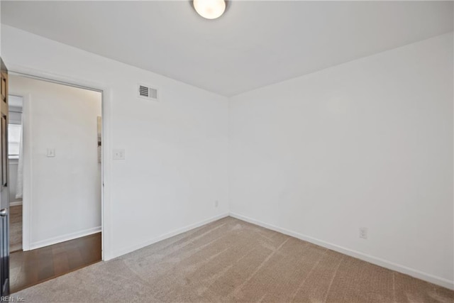 empty room with carpet floors, visible vents, and baseboards