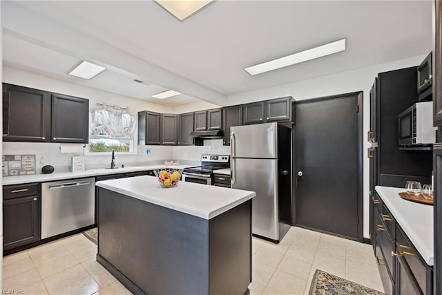 kitchen featuring tasteful backsplash, appliances with stainless steel finishes, light countertops, under cabinet range hood, and a sink