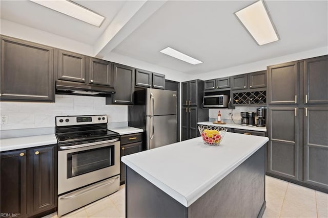 kitchen featuring appliances with stainless steel finishes, light countertops, under cabinet range hood, and decorative backsplash