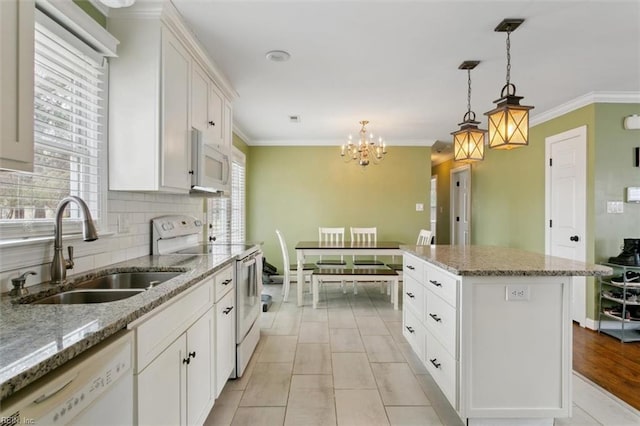 kitchen featuring white appliances, ornamental molding, decorative backsplash, and a sink