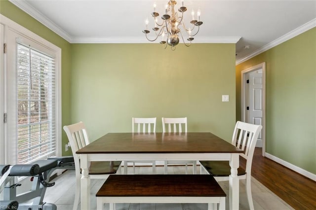 dining room featuring light wood-style floors, a chandelier, crown molding, and baseboards