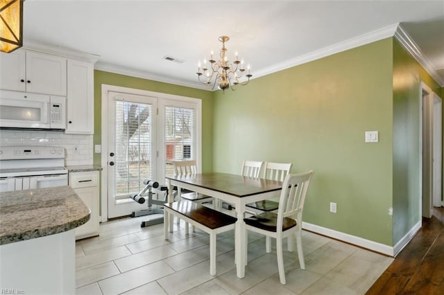 dining room featuring baseboards, visible vents, a chandelier, and ornamental molding