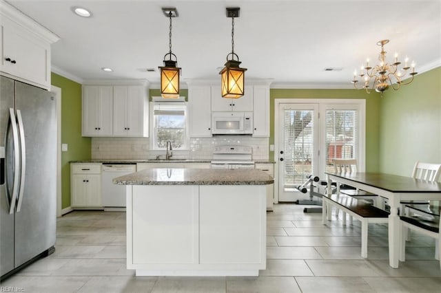 kitchen with white appliances, white cabinets, a center island, crown molding, and a sink