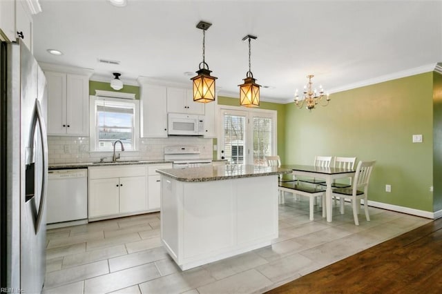 kitchen featuring ornamental molding, white appliances, a sink, and white cabinets