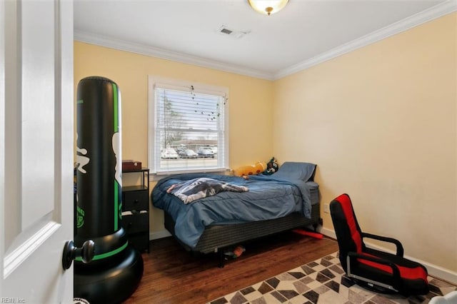 bedroom featuring baseboards, visible vents, ornamental molding, and wood finished floors