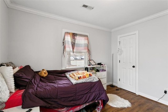 bedroom with baseboards, crown molding, visible vents, and wood finished floors