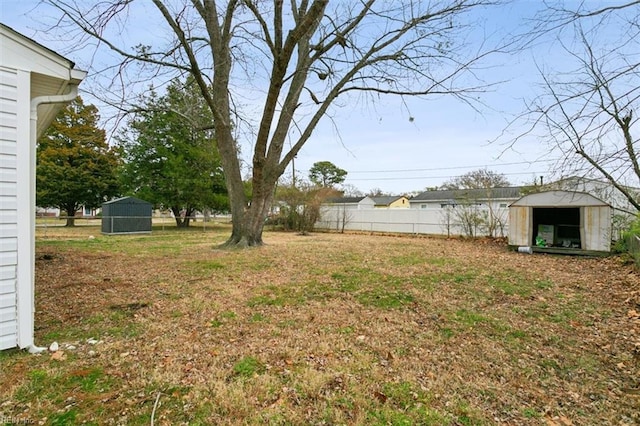 view of yard featuring a shed, fence, and an outbuilding