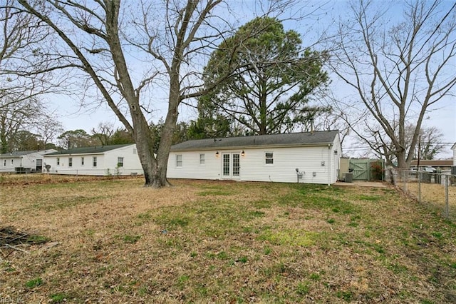 back of property with french doors, a fenced backyard, and a lawn