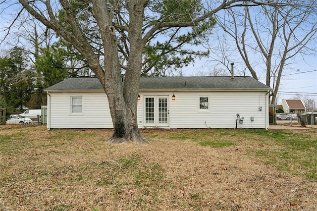 rear view of house featuring fence, a lawn, and french doors