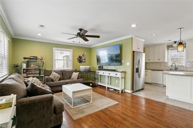 living room featuring recessed lighting, visible vents, crown molding, and light wood finished floors