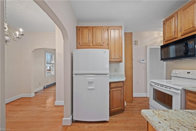 kitchen featuring arched walkways, light wood finished floors, light stone countertops, white appliances, and baseboards