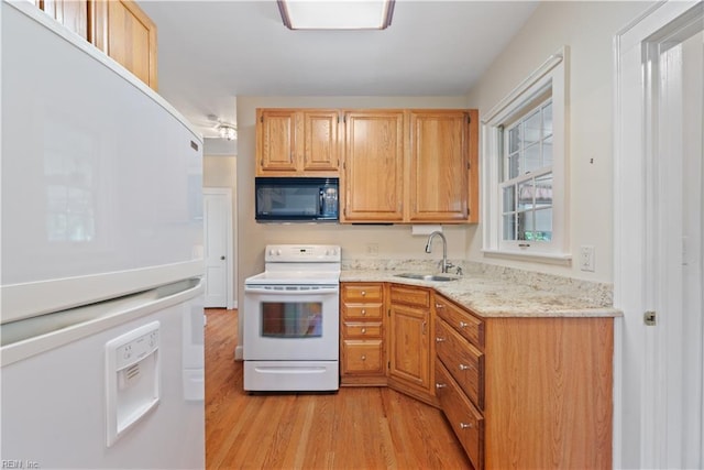 kitchen featuring light wood-type flooring, white appliances, a sink, and light stone countertops