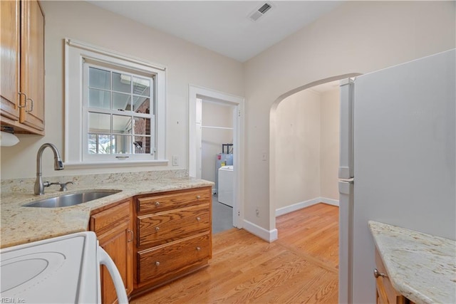 kitchen featuring visible vents, arched walkways, stove, light wood-type flooring, and a sink