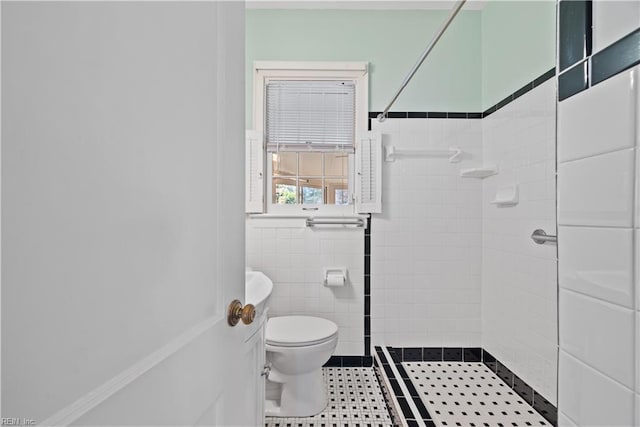 bathroom featuring tiled shower, tile patterned floors, toilet, and tile walls