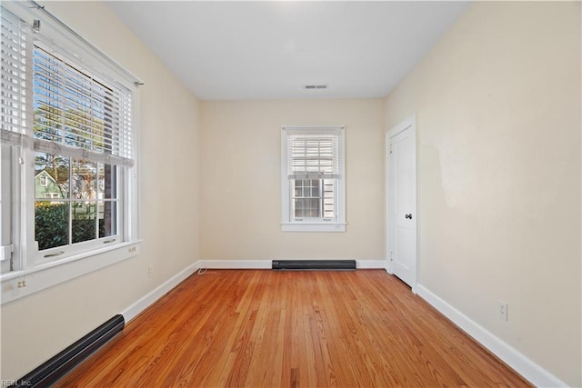 unfurnished room with light wood-style floors, visible vents, and baseboards