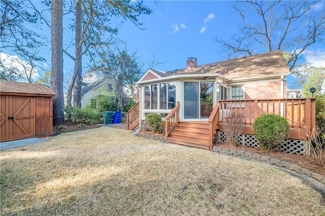 back of property featuring an outbuilding, brick siding, a chimney, a storage unit, and a sunroom