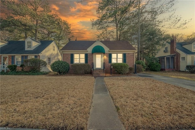 view of front of property featuring brick siding and a lawn