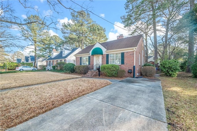 view of front of house with a front yard, a chimney, and brick siding