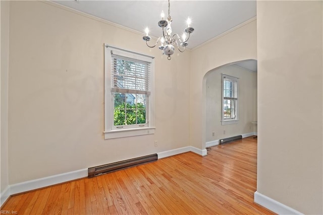 spare room featuring arched walkways, ornamental molding, a baseboard radiator, and wood finished floors