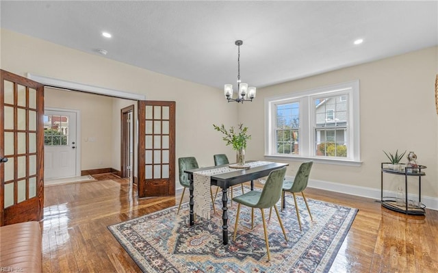 dining space featuring baseboards, a healthy amount of sunlight, an inviting chandelier, and wood finished floors