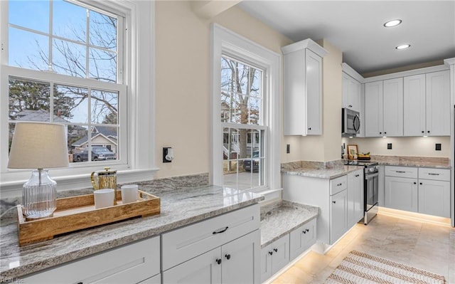 kitchen with white cabinetry, stainless steel appliances, light stone counters, and recessed lighting