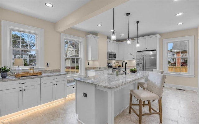 kitchen featuring light stone counters, a sink, visible vents, white cabinets, and appliances with stainless steel finishes