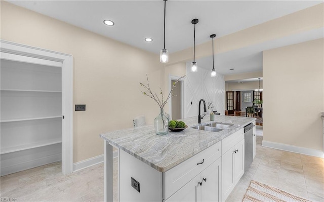 kitchen featuring decorative light fixtures, a sink, light stone countertops, white cabinetry, and stainless steel dishwasher