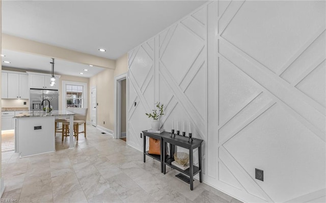 kitchen with a breakfast bar, marble finish floor, white cabinets, an island with sink, and stainless steel fridge with ice dispenser